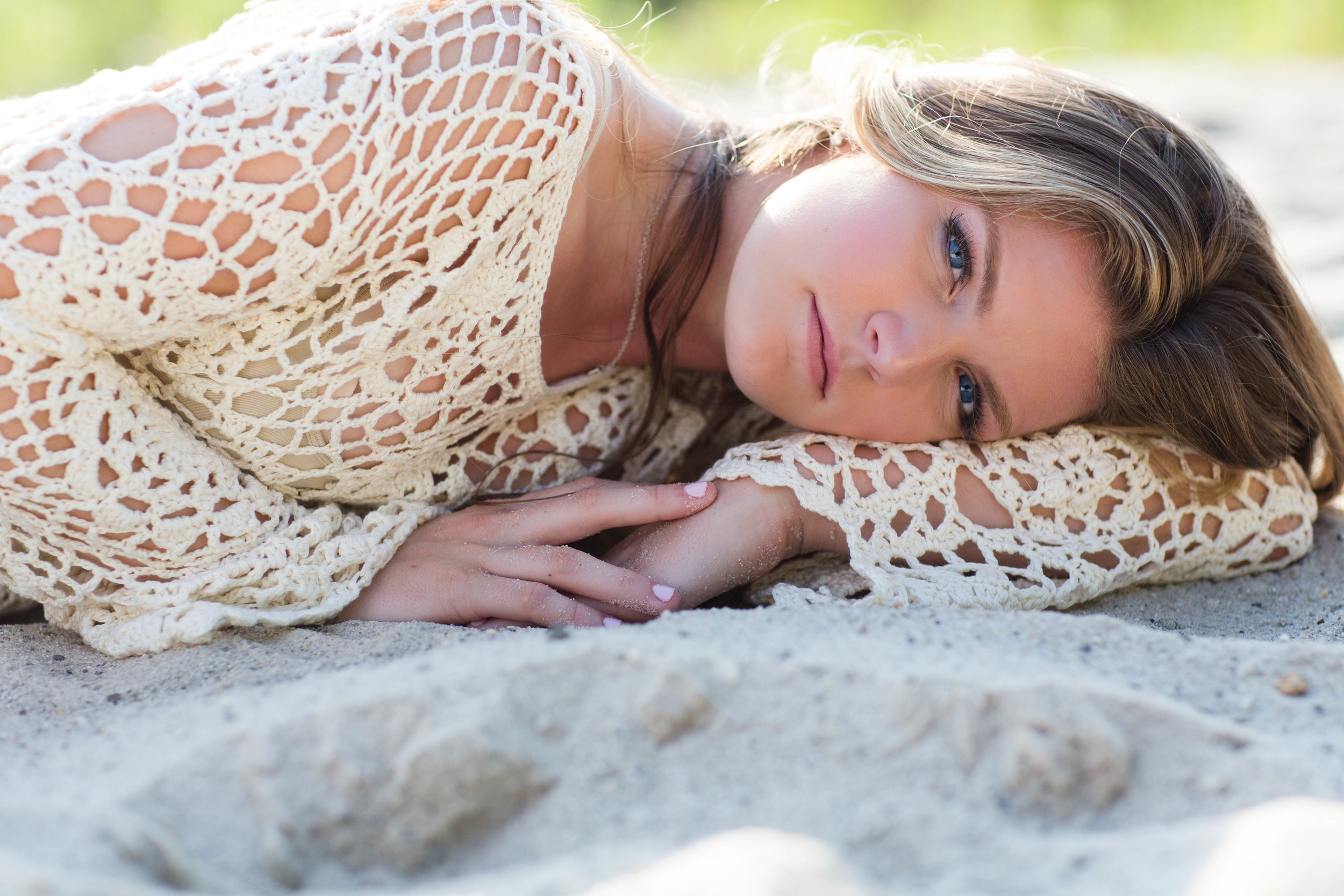 Teen portrait of a girl laying in the sand at beach